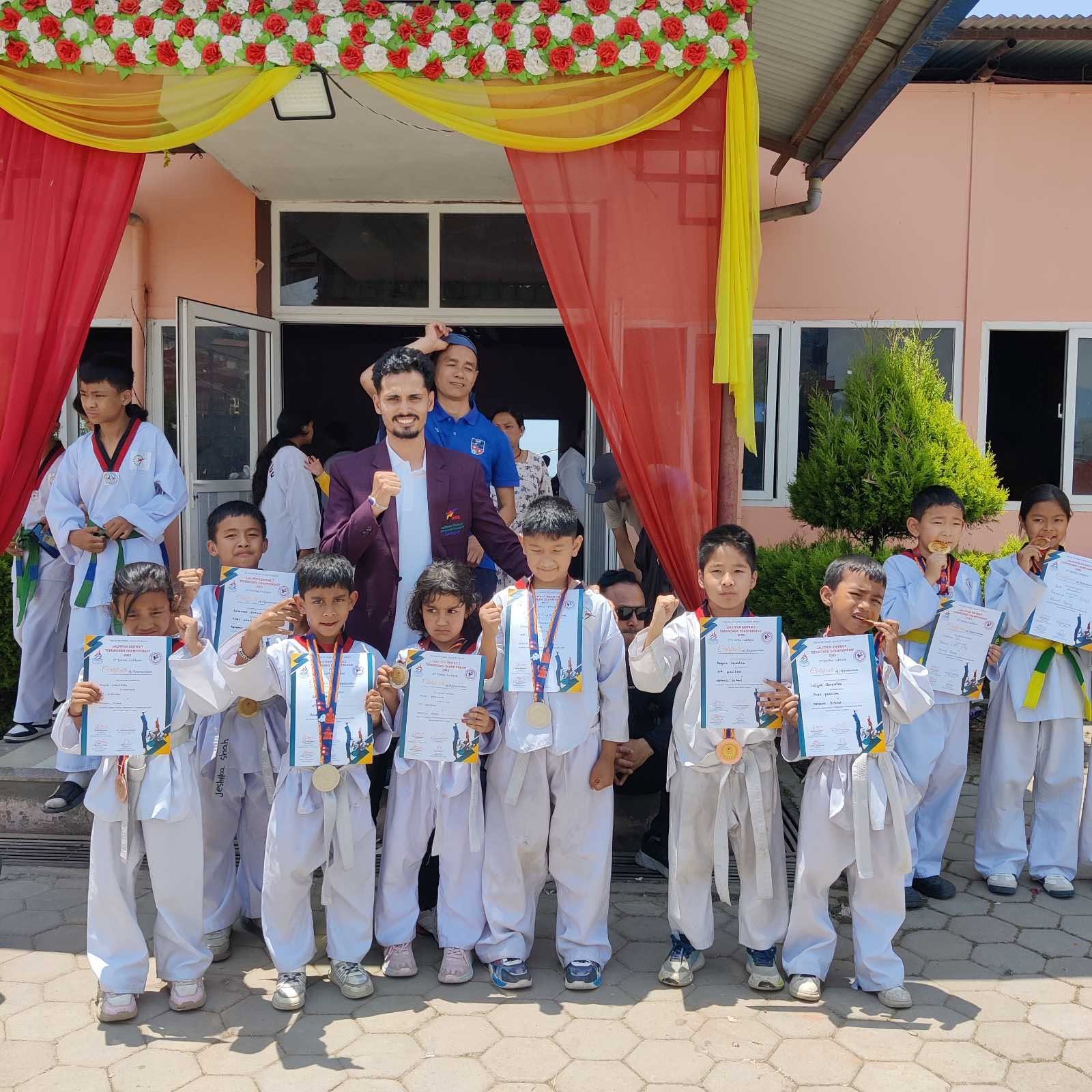 Students proudly showing their taekwondo certificates and medals outside the school