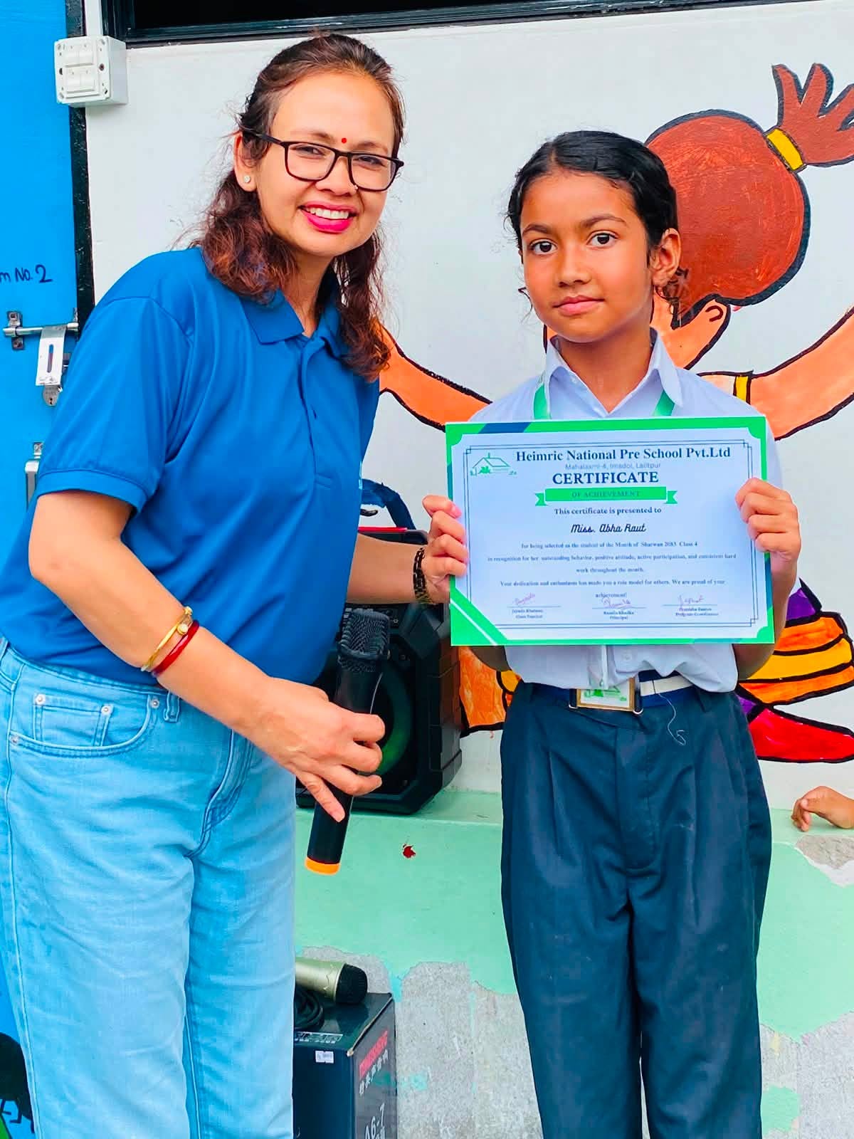 A Heimric student receiving her Student of the Month certificate from her teacher