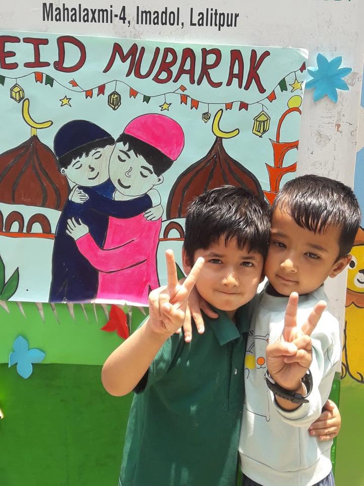 Two students posing in front of the school's Eid Mubarak display