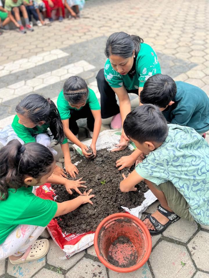 Children digging in the soil with their teacher during a gardening activity