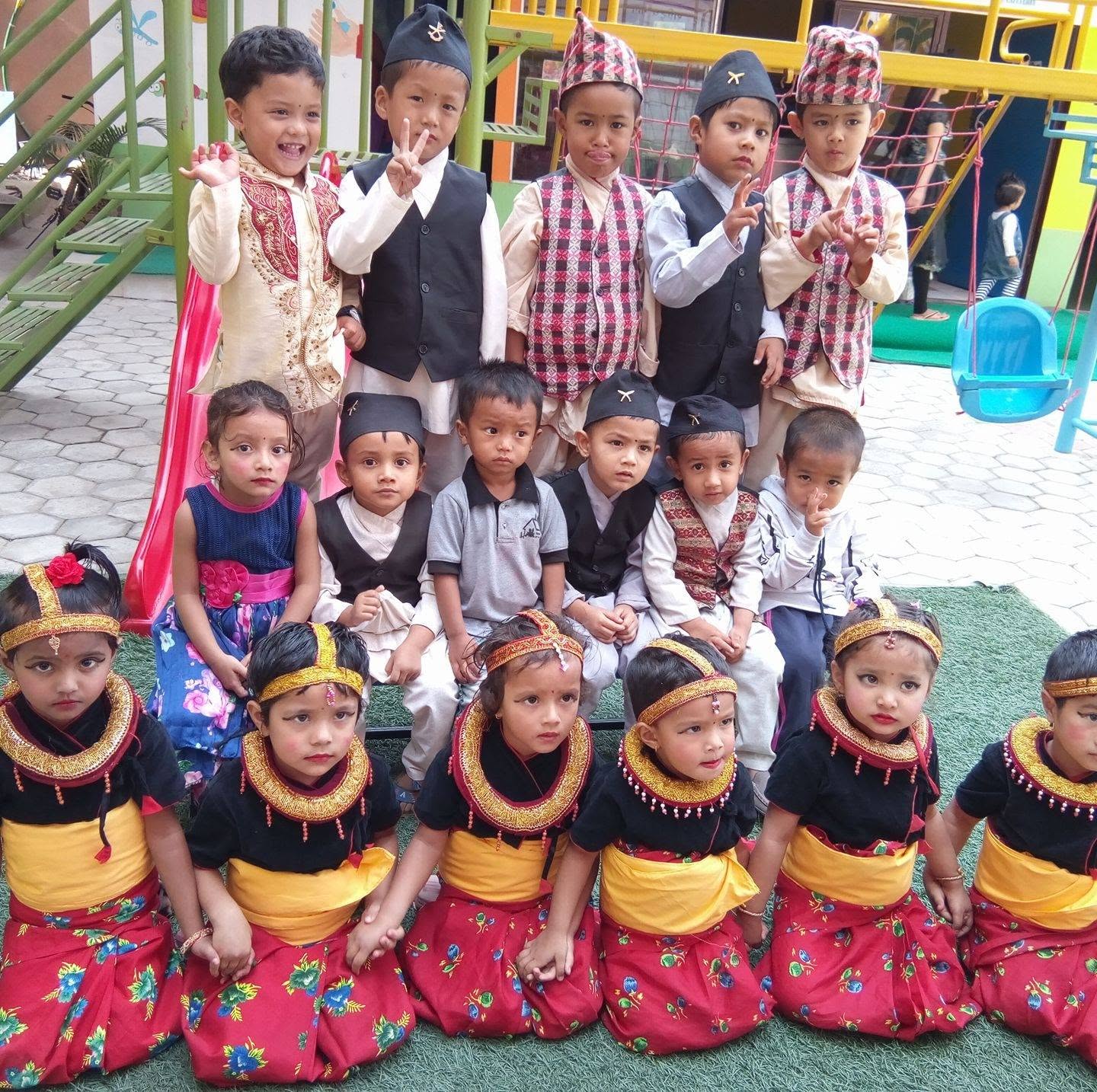 Children in traditional Nepali dress posing together in the school playground