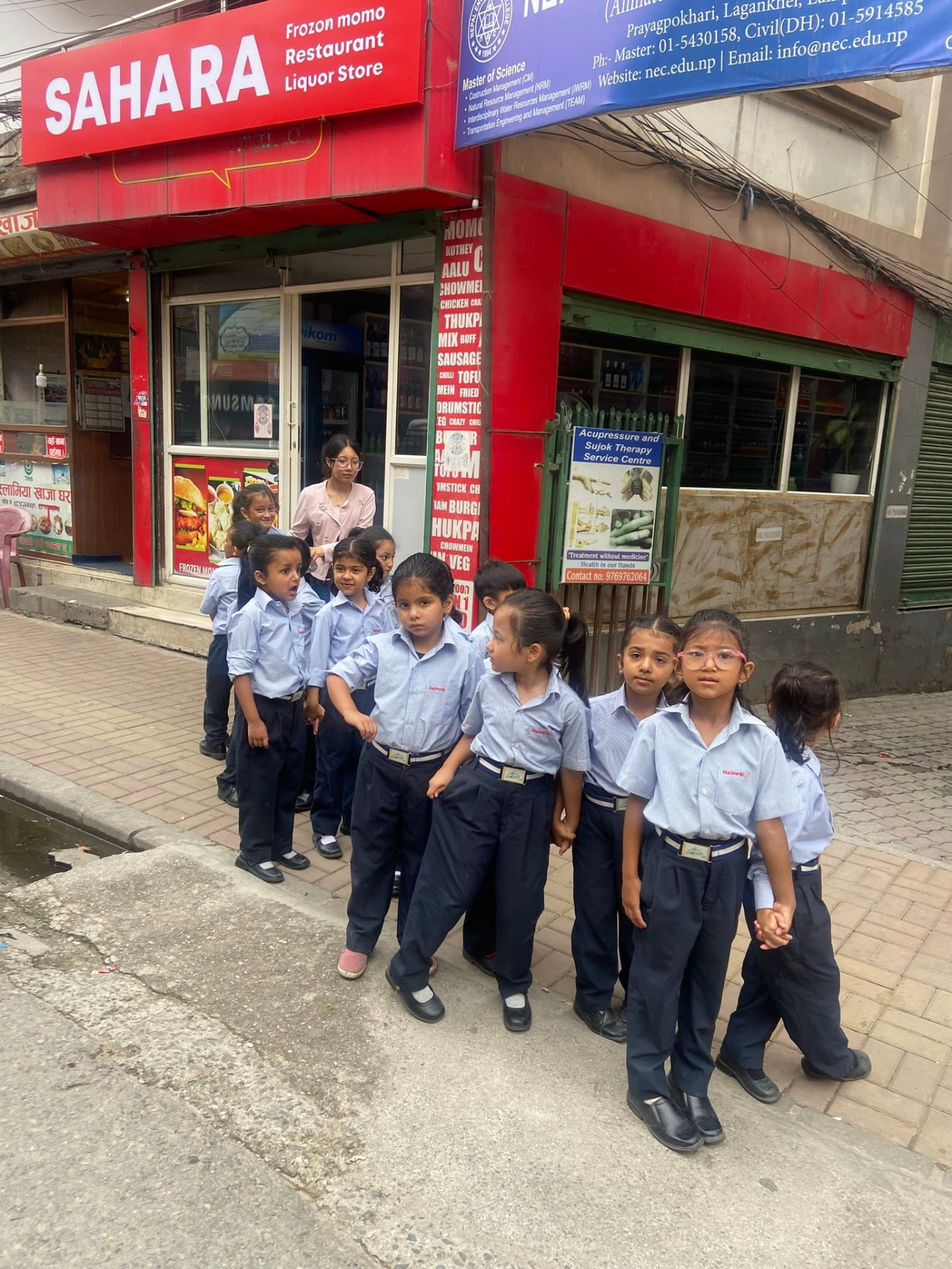 Heimric students in uniform walking in line with their teacher during a neighbourhood field trip