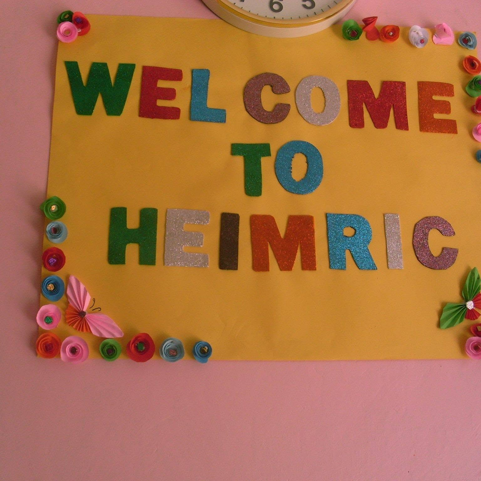 Handmade 'Welcome to Heimric' board decorated with paper flowers in a classroom