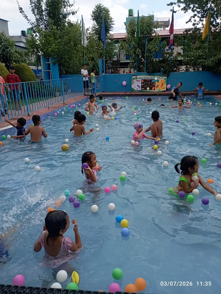 Children splashing among colourful balls during the school swimming fun day