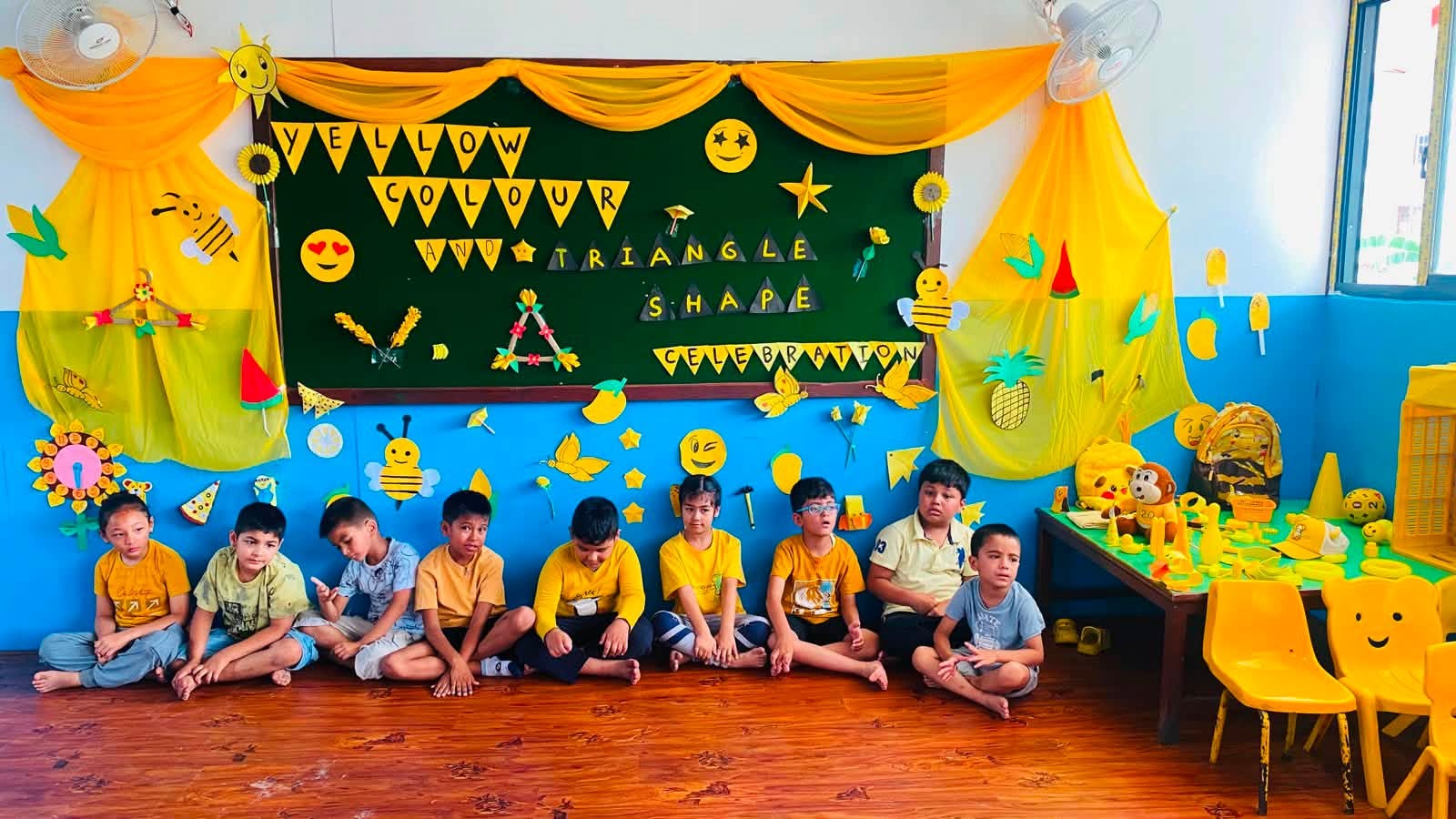 Students dressed in yellow sitting beneath the Yellow Colour and Triangle Shape celebration display