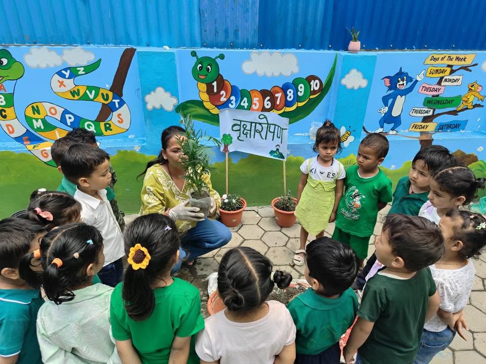 Children and their teacher planting a tree in front of the school's educational mural